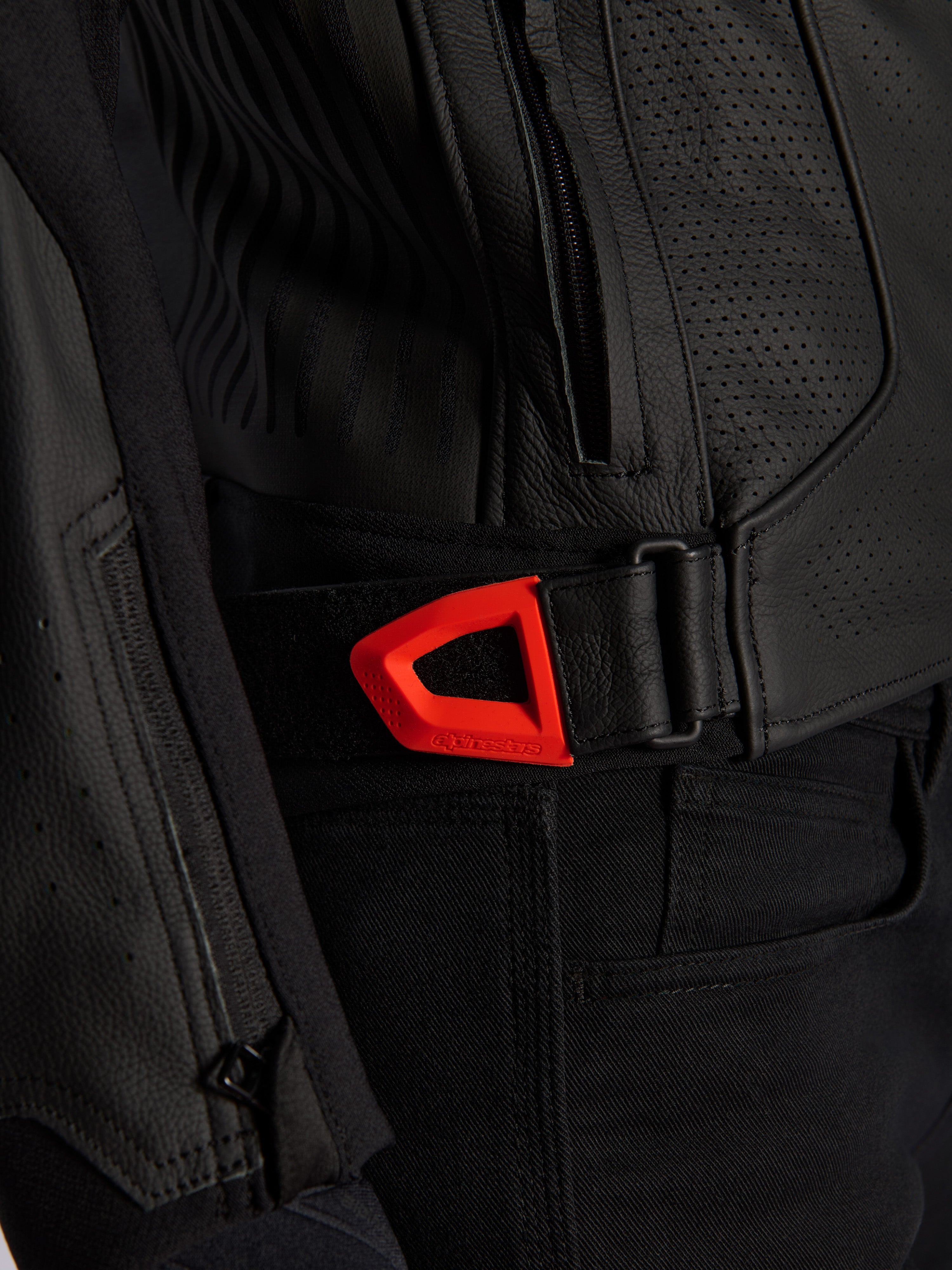 Alpinestars GP Plus R V4 Airflow leren jas close-up, zwart geperforeerd leer met een opvallende rood fluo klittenband verstelband voor de taille, voorzien van een zijzak met ritssluiting en ergonomische panelen met textuur