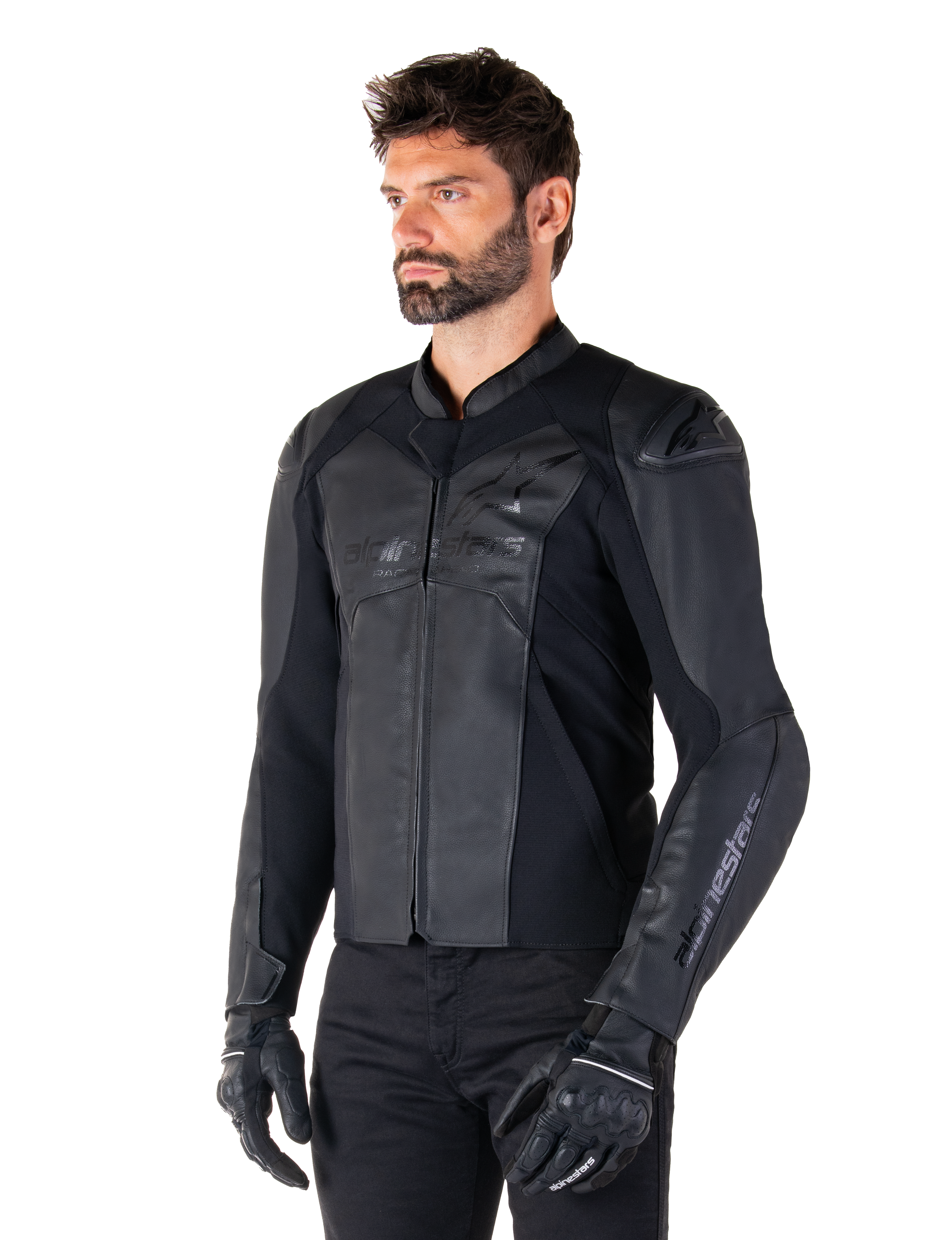 Alpinestars Faster V3 Leren Jas, sportief motorjack, zwart zwart, gedragen door een mannelijk model met zwarte broek en handschoenen, hoogwaardige leren constructie met stretchpanelen en DFS GP Lite schouderbeschermers, strak en modern sportief silhouet