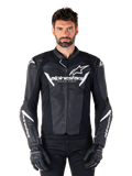 Alpinestars Faster V3 leren jas, zwart-wit motorracejack, voorzien van opvallende witte logo's en 'Racing Ahead' tekst op de borst, strak leren ontwerp met hoekige accenten op de mouwen, gedragen met zwarte racehandschoenen