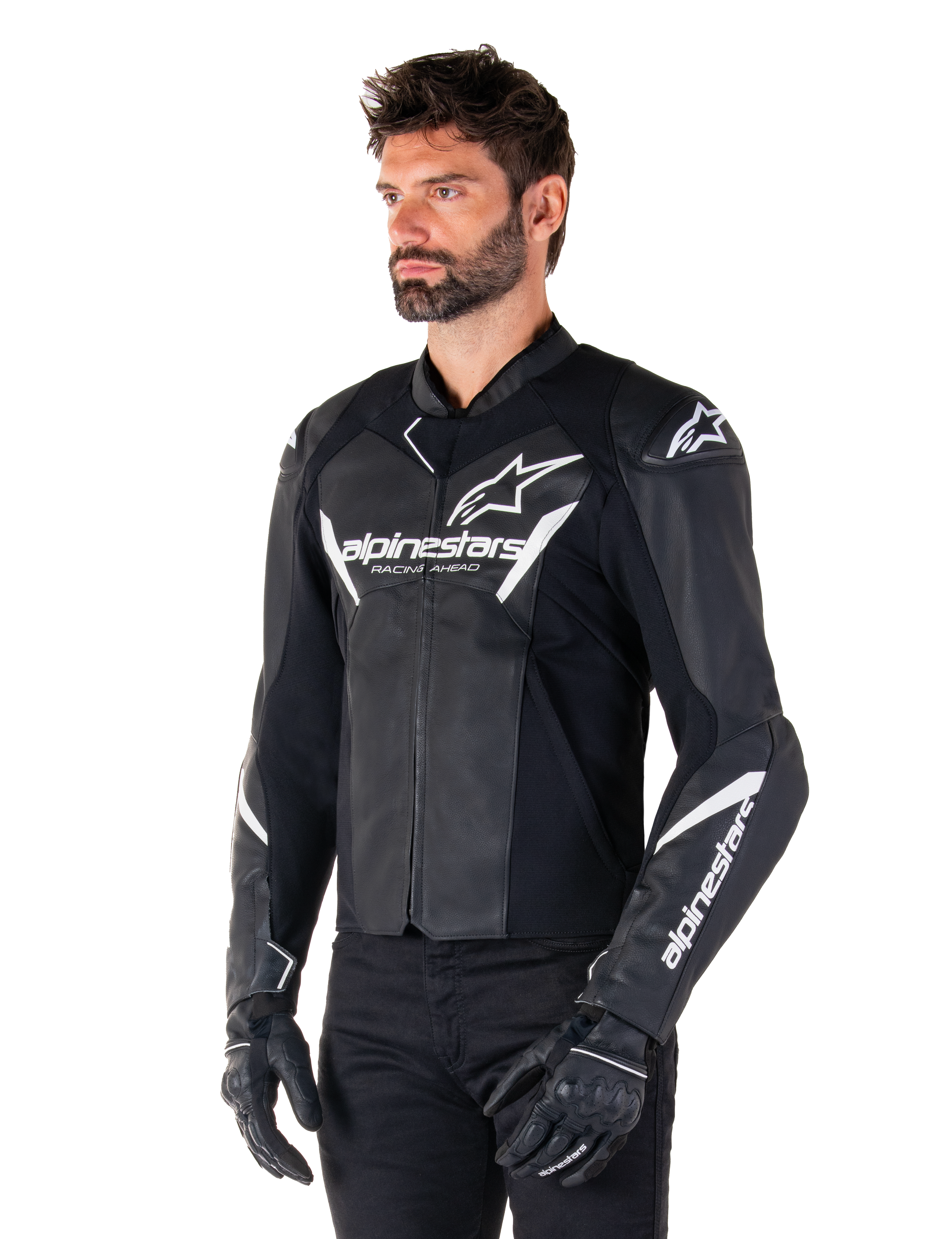 Alpinestars Faster V3 leren jas, sportieve motorjas, zwart en wit, prominent wit Alpinestars-logo en 'Racing Ahead'-tekst op de borst, sterlogo's op de schouders, hoogwaardige leren constructie met stretchpanelen, gedragen door een model met zwarte broek en handschoenen