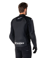Alpinestars Faster V3 Leren Jas, zwart en wit, achteraanzicht op een rijder, met wit sterlogo op de bovenrug en groot Alpinestars-logo met "Racing Ahead" op de onderzijde van de rug, verlengde achterzijde voor extra bedekking tijdens het rijden, hoogwaardige sportleren constructie