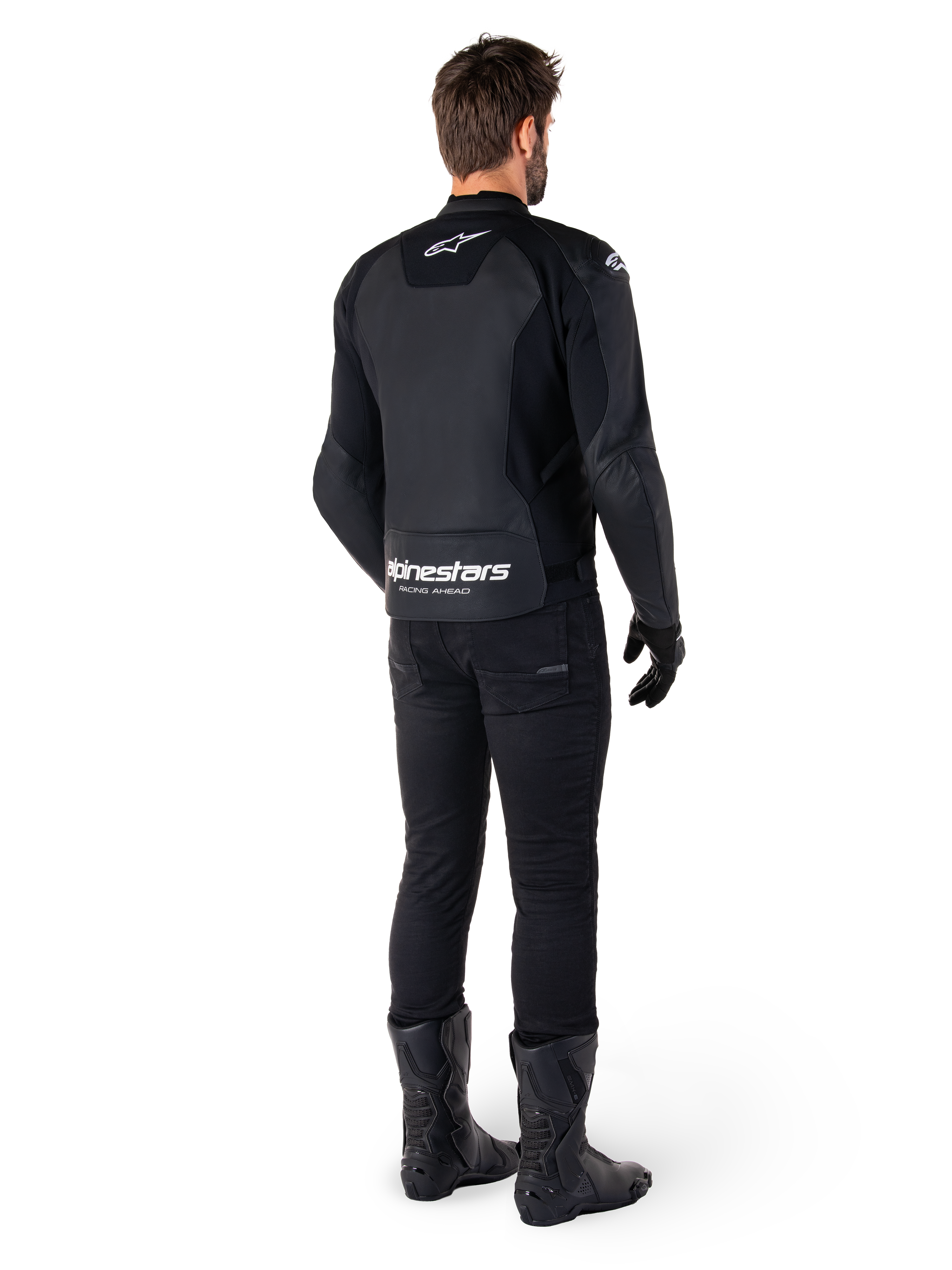 Alpinestars Faster V3 Leren Jas, achteraanzicht, zwart en wit, met 'alpinestars RACING AHEAD' branding op de onderrug, gedragen met zwarte motorbroek en laarzen, sportieve leren motorjas met stretchpanelen.