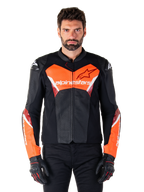 Alpinestars Faster V3 Airflow leren jas, motorracejas, zwart en fluo rood, geperforeerde leren constructie met witte en rode accenten, gedragen met zwarte handschoenen, performance motorkleding voor op de weg