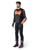 Alpinestars Faster V3 Airflow leren jas, zwart en fluo rood, gedragen door een mannelijk model met zwarte motorbroek, handschoenen en racelaarzen, voorzien van geperforeerd leer en een sportief silhouet.