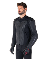 Model draagt de Alpinestars Faster V3 Airflow Leren Jas in Black Black, sportief motorjack met geperforeerd leer en stretchpanelen, gecombineerd met een zwarte broek en zwarte handschoenen met rode accenten, strakke op de racerij geïnspireerde stijl.