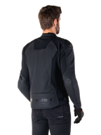 Alpinestars Faster V3 Airflow Leren Jas, zwart, achteraanzicht van een man die een sportief leren motorjack draagt, voorzien van geperforeerde rugpanelen, stretch-inzetstukken en Alpinestars-branding op de onderste zoom, gecombineerd met een zwarte broek en handschoenen