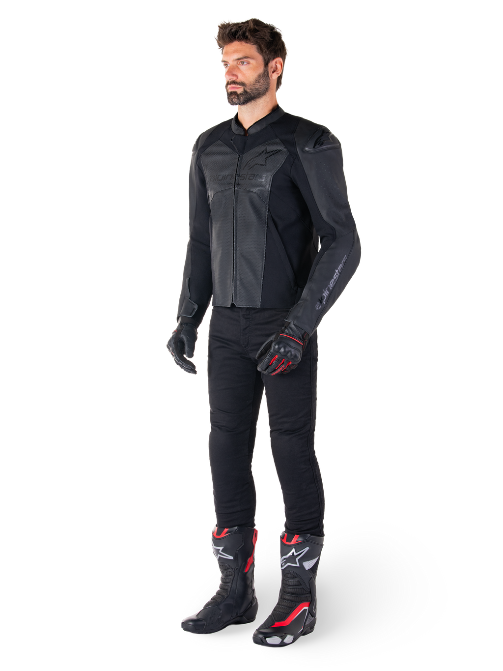 Man die Alpinestars Faster V3 Airflow leren jas in Black Black draagt, gecombineerd met een zwarte broek, zwart-rode motorhandschoenen en zwarte racelaarzen met rode en witte accenten, volledige sportieve motoruitrusting