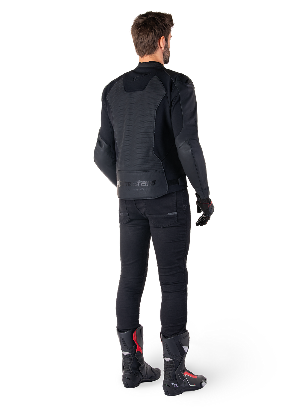 Alpinestars Faster V3 Airflow Leren Jas, zwart, achteraanzicht van een man die een sportieve leren jas draagt met geperforeerde rugpanelen en Alpinestars-branding, gecombineerd met een zwarte rijbroek en zwart-rode laarzen.