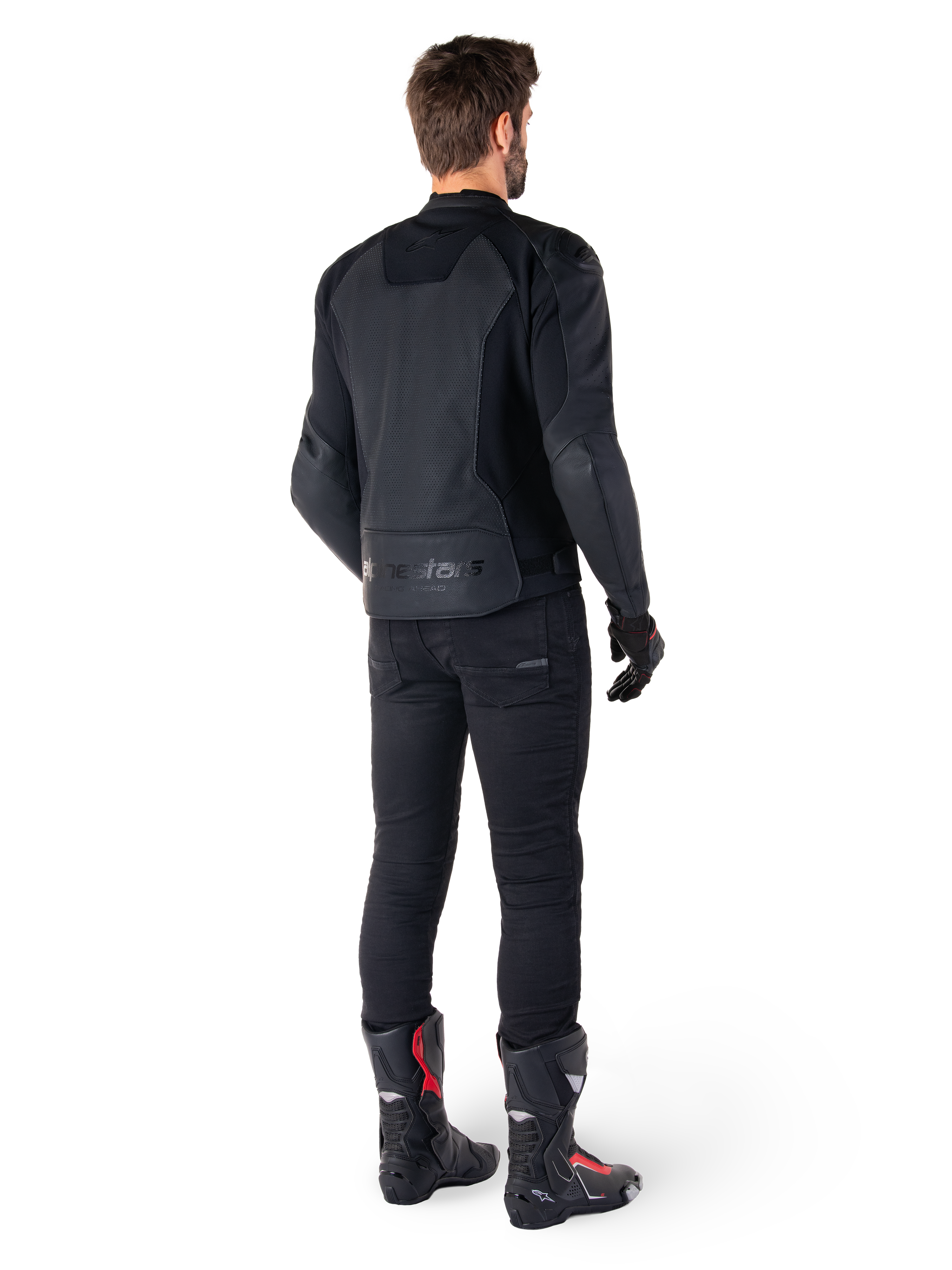Alpinestars Faster V3 Airflow Leren Jas, zwart, achteraanzicht van een man die een sportieve leren jas draagt met geperforeerde rugpanelen en Alpinestars-branding, gecombineerd met een zwarte rijbroek en zwart-rode laarzen.