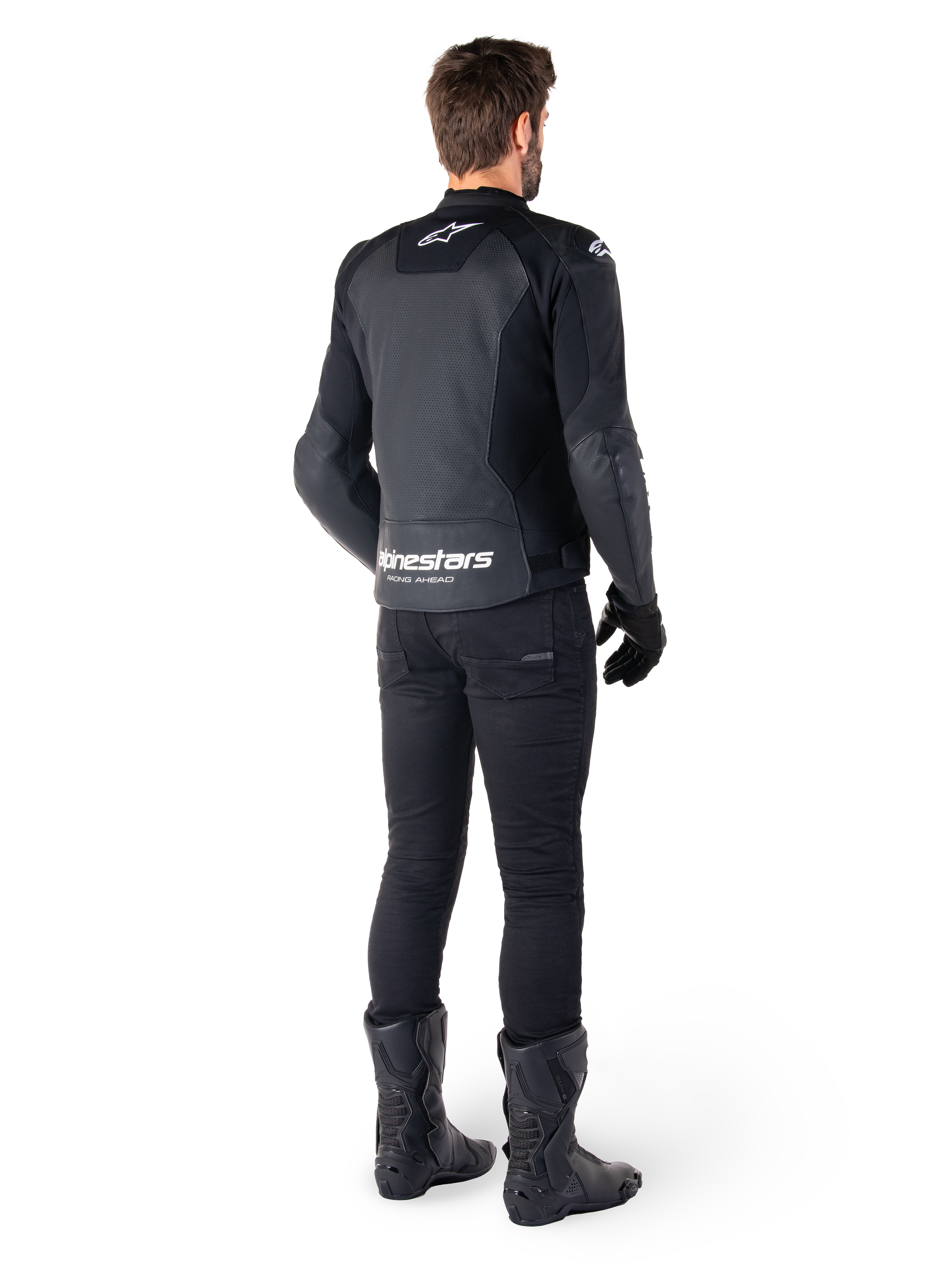 Alpinestars Faster V3 Airflow leren jas, zwart en wit, achteraanzicht met geperforeerde leren panelen en opvallende Alpinestars-branding op de onderrug, gedragen door een motorrijder met zwarte motorbroek, handschoenen en laarzen