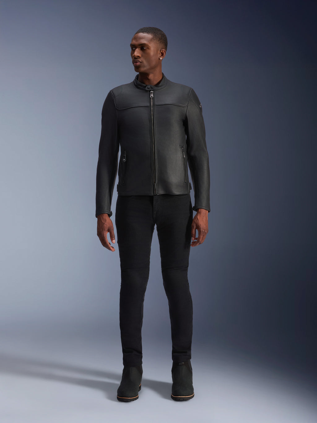 Mannelijk model draagt Alpinestars Blacktrack Leren Jas, zwart premium rundleer, modern minimalistisch bikerontwerp met een op maat gemaakte pasvorm, gecombineerd met een zwarte motorbroek en laarzen, urban contemporary stijl