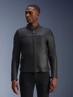 Alpinestars Blacktrack leren motorjas, zwart, gedragen door een model, voorzien van een metalen ritssluiting aan de voorzijde, hoge kraag en zakken met rits, strakke premium leren constructie voor een moderne minimalistische look