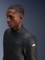 Alpinestars Blacktrack leren jas, hoogwaardig zwart rundleer, close-up profielaanzicht van een man die de jas draagt, voorzien van een metallic gunmetal rits, hoge kraag met knoopsluiting en metalen schouderembleem met logo, strakke getailleerde motorjas