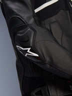 Alpinestars Atem V5 Leren Jas, zwart en wit, close-up van de DFS RR elleboogbeschermer met wit ster-logo, voorzien van accordeonleer en geperforeerde texturen voor sportief rijden
