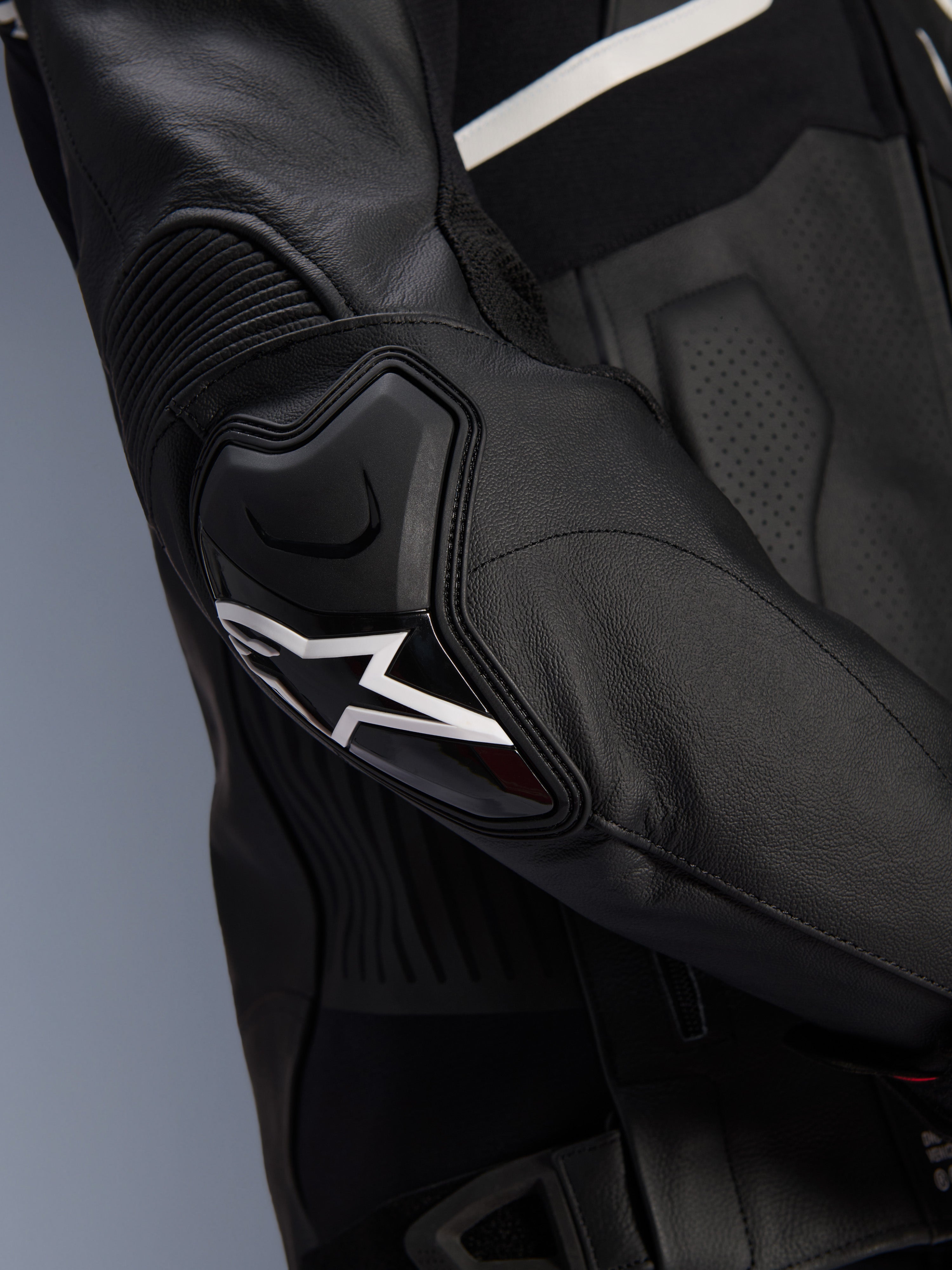 Alpinestars Atem V5 Leren Jas, zwart en wit, close-up van de DFS RR elleboogbeschermer met wit ster-logo, voorzien van accordeonleer en geperforeerde texturen voor sportief rijden