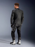 Alpinestars Caliber leren jas, zwarte motorjas, achteraanzicht, voorzien van geperforeerd leer en accordeon stretch-inzetten in de taille en op de schouders, logo in reliëf, gedragen met zwarte leren broek en witte racelaarzen