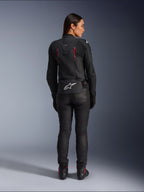 Alpinestars Stella Dusk leren motorjas, achteraanzicht, zwart leer met Diva Pink en witte accenten, voorzien van een wit Alpinestars-logo op de onderrug en roze ventilatiedetails, gedragen met een zwarte motorbroek en laarzen, hoogwaardige sportieve motoruitrusting voor dames