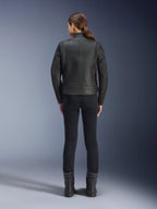 Achteraanzicht van een vrouw die de Alpinestars Stella Dyno leren jas draagt, zwart met Haute Red-accenten, gecombineerd met een zwarte slim-fit broek en zwarte laarzen, modern heritage leren motorjasontwerp.