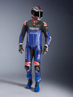 Alpinestars Yamaha GP-R7 eendelig leren racepak, motorracepak, metallic blauw en zwart met rode en witte accenten, voorzien van Yamaha- en GYTR-branding, gedragen met bijpassende helm, racehandschoenen en blauwe laarzen, professionele performance uitrusting