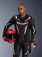 Alpinestars GP Force V2 Leren Pak, 1-delig motorpak, zwart, wit en fluorood, gedragen door een model dat een rode helm en handschoenen vasthoudt, strak race-ontwerp met geperforeerd leer en opvallende branding