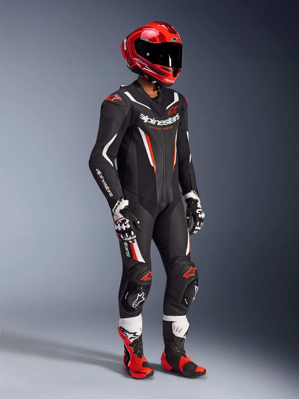 Alpinestars GP Force V2 Leren Pak - 1-delig, professioneel racepak in zwart, wit en fluo rood, voorzien van geperforeerde leren panelen en DFS Lite-schilden, complete circuit-uitrusting met rode racehelm, bijpassende handschoenen en laarzen.