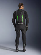Achteraanzicht van het Alpinestars GP Force V2 1-delig leren pak in zwart en groen, voorzien van een aerodynamische speed hump, geperforeerde panelen en Tech-Air Ready-branding op de onderrug, gedragen met zwarte racehandschoenen en laarzen.