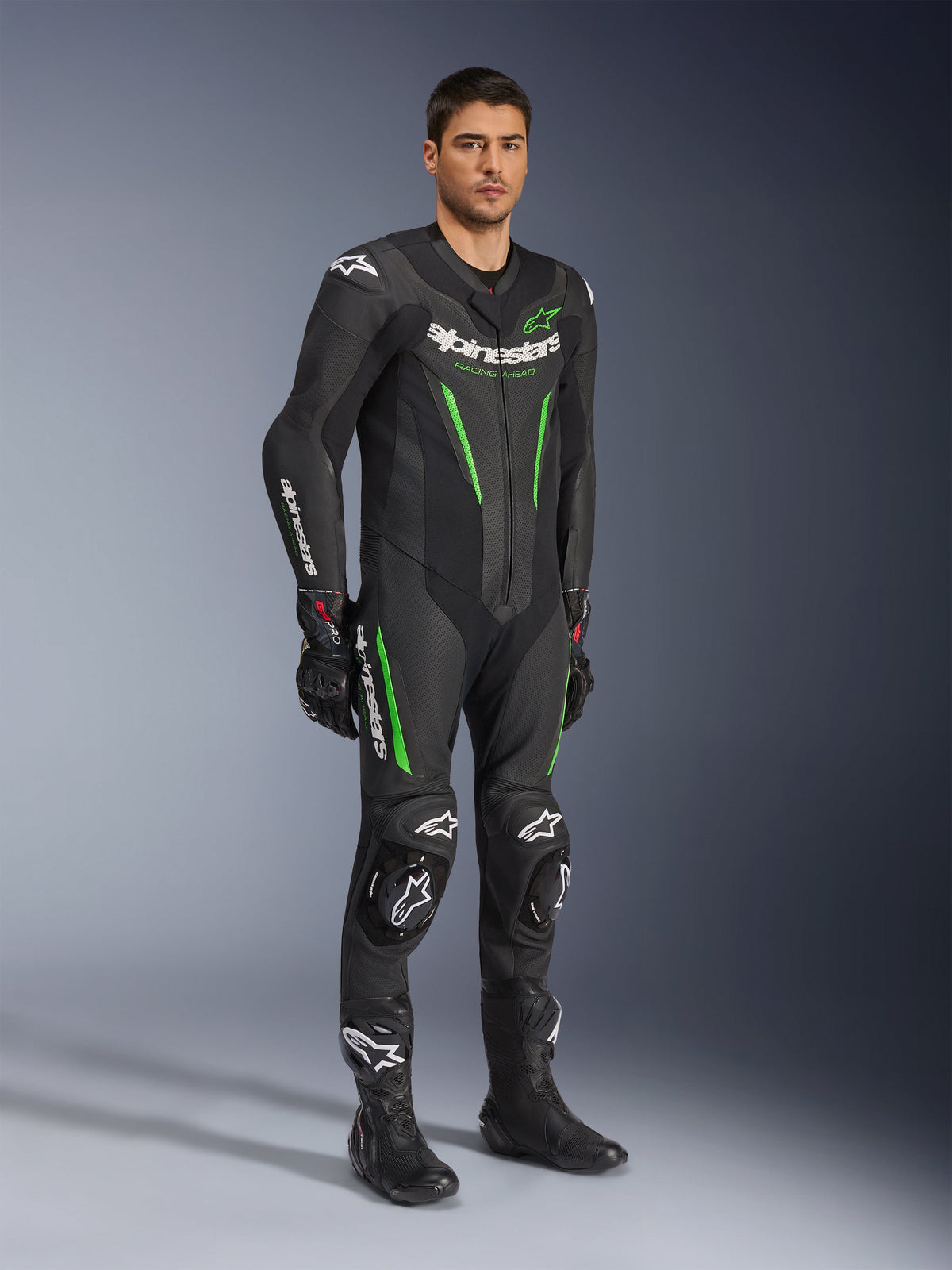 Alpinestars GP Force V2 Leren Pak 1-delig, zwart en groen, volledige race-uitrusting gedragen met zwarte handschoenen en laarzen, voorzien van geperforeerde leren panelen, witte Alpinestars-branding en geïntegreerde kniesliders, professioneel racepak voor circuitprestaties