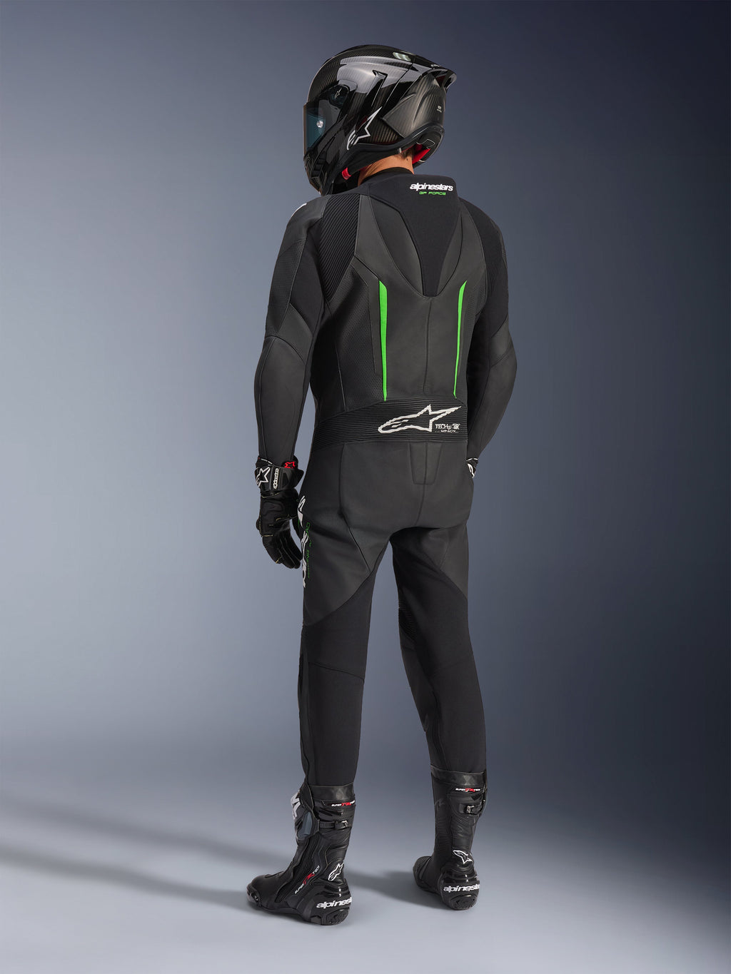 Rijder van achteren gezien in Alpinestars GP Force V2 Leren Pak, 1-delig, zwart met groene accenten, aerodynamische speed hump, gecombineerd met een zwarte carbon helm, zwarte racelaarzen en handschoenen, hoogwaardige motorrace-uitrusting