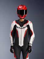Alpinestars GP Force V2 Leren Pak - 1-delig, wit zwart rood fluo, gedragen met een rode integraalhelm en zwarte racehandschoenen, voorzien van geperforeerde leren panelen en opvallende Alpinestars-branding op de borst, professionele uitrusting voor motorraces