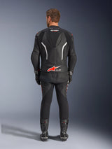 Achteraanzicht van een rijder in het Alpinestars GP Force V2 tweedelig leren pak, zwart met witte en rode accenten, opvallende Alpinestars en Tech-Air Ready branding op de rug, gestyled met bijpassende zwarte racehandschoenen en laarzen