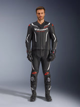 Alpinestars GP Force V2 tweedelig leren pak, motorracepak, zwart, wit en fluo rood, gedragen door een model met bijpassende zwarte handschoenen en laarzen, voorzien van geperforeerde leren panelen, witte en fluo rode accenten en een strak aerodynamisch ontwerp voor circuit- en sportrijden