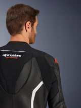 Alpinestars GP Force V2 tweedelig leren pak, close-up van de bovenrug en schouder op een mannelijk model, zwart leer met witte en rode accenten, Alpinestars GP Force-branding, met geperforeerde panelen en accordeon-stretchzones voor motorracen