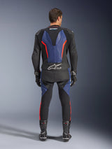 Alpinestars GP Force V2 tweedelig leren pak, achteraanzicht, zwart, blauw en fluorood, voorzien van blauwe lederen panelen op de rug en benen met fluorescerend rode accenten, Tech-Air Ready branding op de onderrug, gedragen met zwarte racehandschoenen en laarzen.
