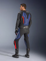 Alpinestars GP Force V2 leren pak (2-delig), zwart, blauw en fluo rood, achteraanzicht op een model, met aerodynamische hump, geperforeerd leer en Tech-Air Ready-branding, gedragen met zwarte Alpinestars racelaarzen en handschoenen.