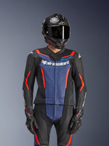 Alpinestars GP Force V2 2-delig leren pak, zwart, blauw en fluo rood, gedragen met een carbon helm en racehandschoenen, voorzien van geperforeerde lederen panelen en wit Alpinestars-logo op de borst, professionele race- en sportuitrusting
