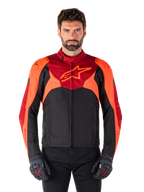 Alpinestars T-Jaws V4 Waterproof Jacket, sportieve textiele motorjas, zwart met felrode en donkerrode accenten, gedragen door een mannelijk model met bijpassende handschoenen, technische motoruitrusting met opvallend sterlogo op de borst.