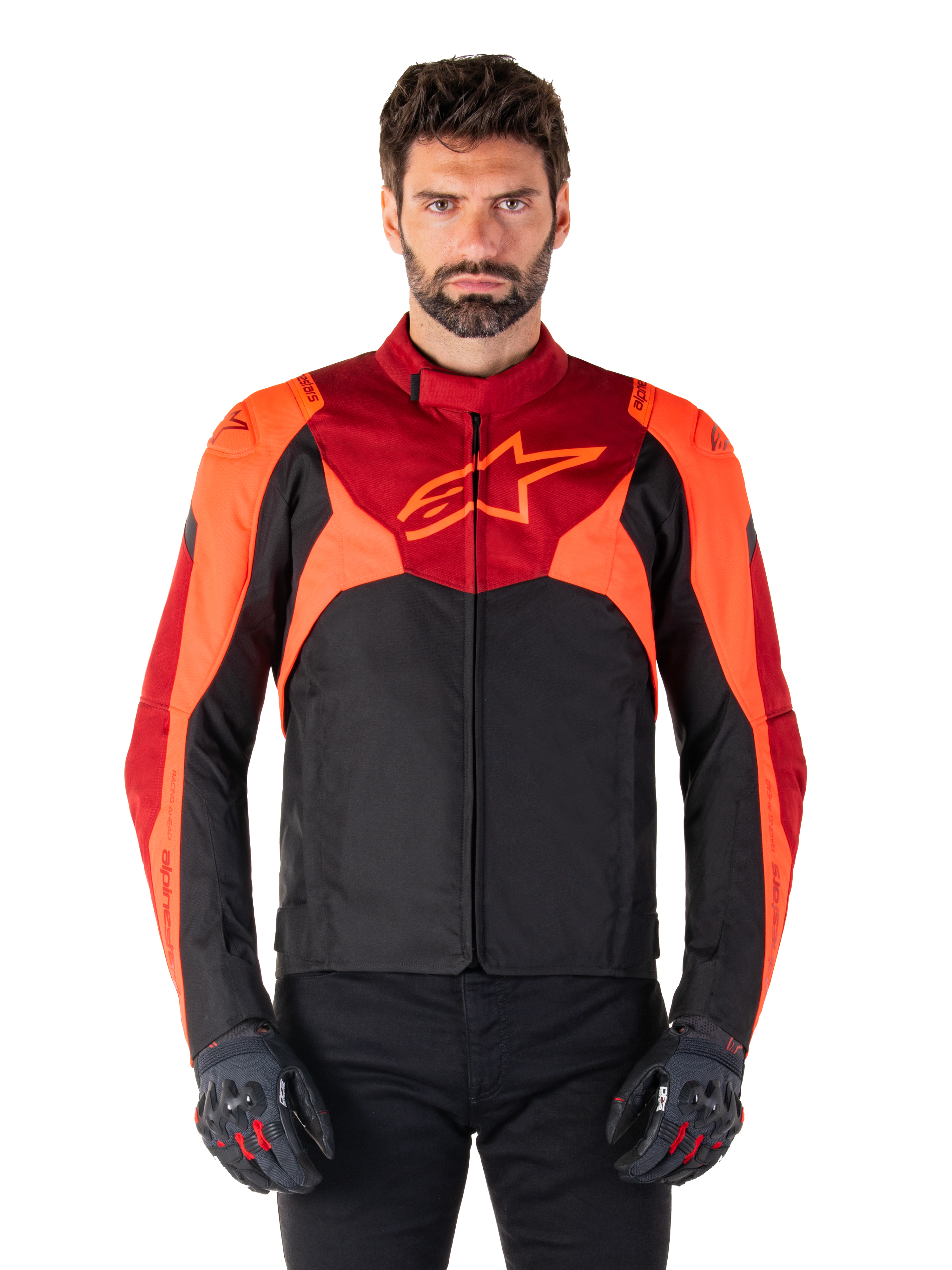 Alpinestars T-Jaws V4 Waterproof Jacket, sportieve textiele motorjas, zwart met felrode en donkerrode accenten, gedragen door een mannelijk model met bijpassende handschoenen, technische motoruitrusting met opvallend sterlogo op de borst.