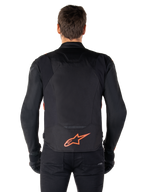 Alpinestars T-Jaws V4 Waterproof Jacket, achteraanzicht, zwart met fluo rood, voorzien van een rood Alpinestars-logo op de onderrug, technische textielconstructie, gedragen met een zwarte broek en handschoenen voor een complete sportieve rijlook