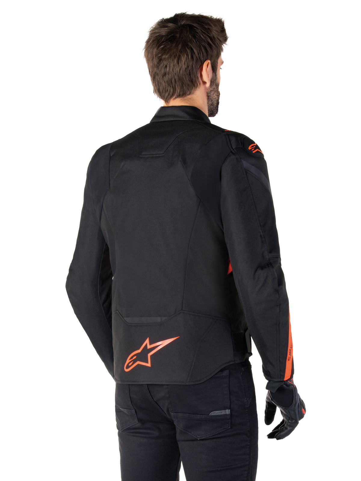 Mannelijk model draagt de Alpinestars T-Jaws V4 Waterproof Jacket vanaf de achterkant, zwart met Red Fluo accenten, voorzien van een rood fluo logo op de onderrug en accenten op de schouders en mouwen, sportieve motoruitrusting.