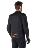 Mannelijk model draagt de Alpinestars T-Jaws V4 Waterproof Jacket vanaf de achterkant, zwart met Red Fluo accenten, voorzien van een rood fluo logo op de onderrug en accenten op de schouders en mouwen, sportieve motoruitrusting.