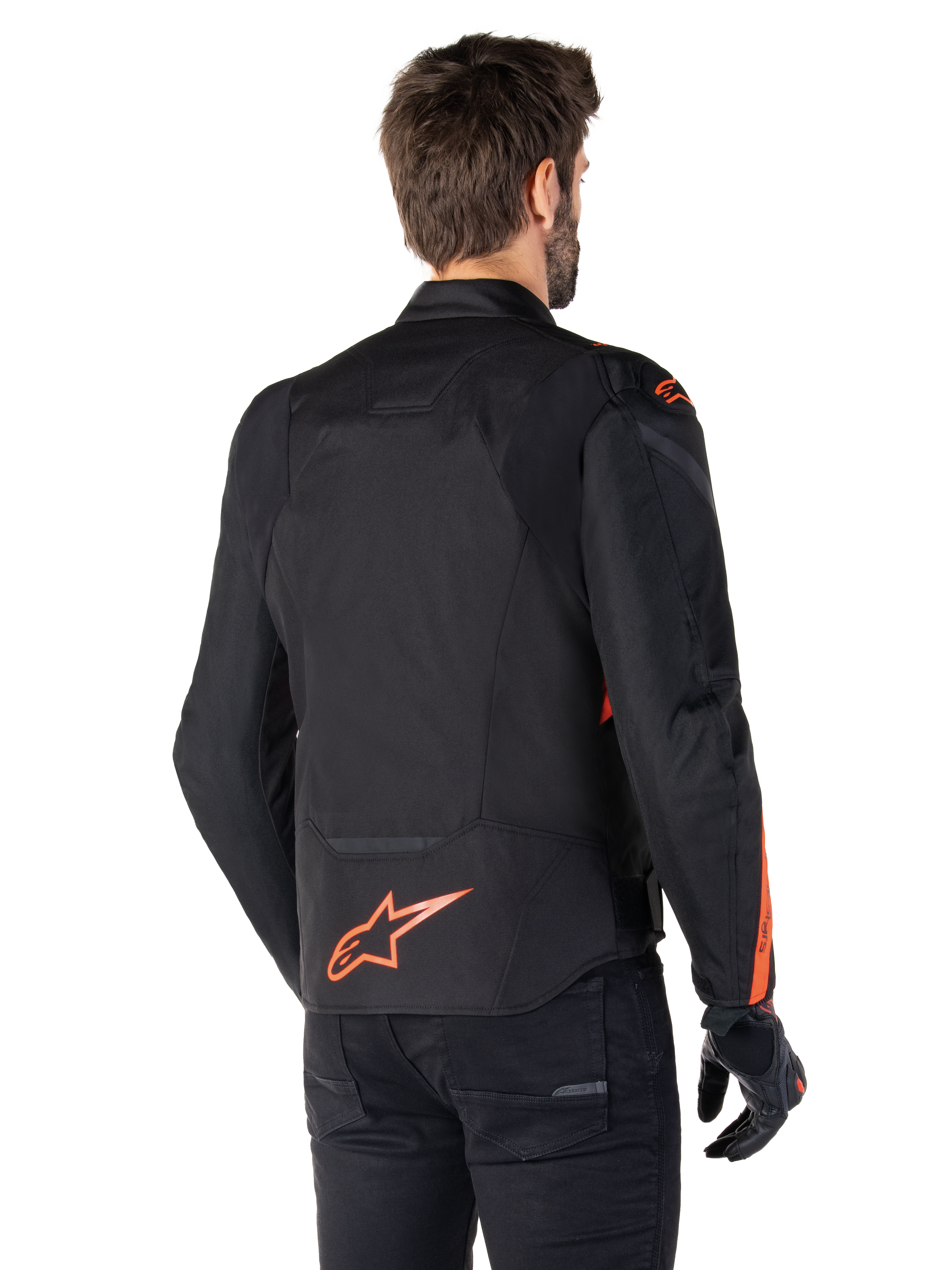 Mannelijk model draagt de Alpinestars T-Jaws V4 Waterproof Jacket vanaf de achterkant, zwart met Red Fluo accenten, voorzien van een rood fluo logo op de onderrug en accenten op de schouders en mouwen, sportieve motoruitrusting.