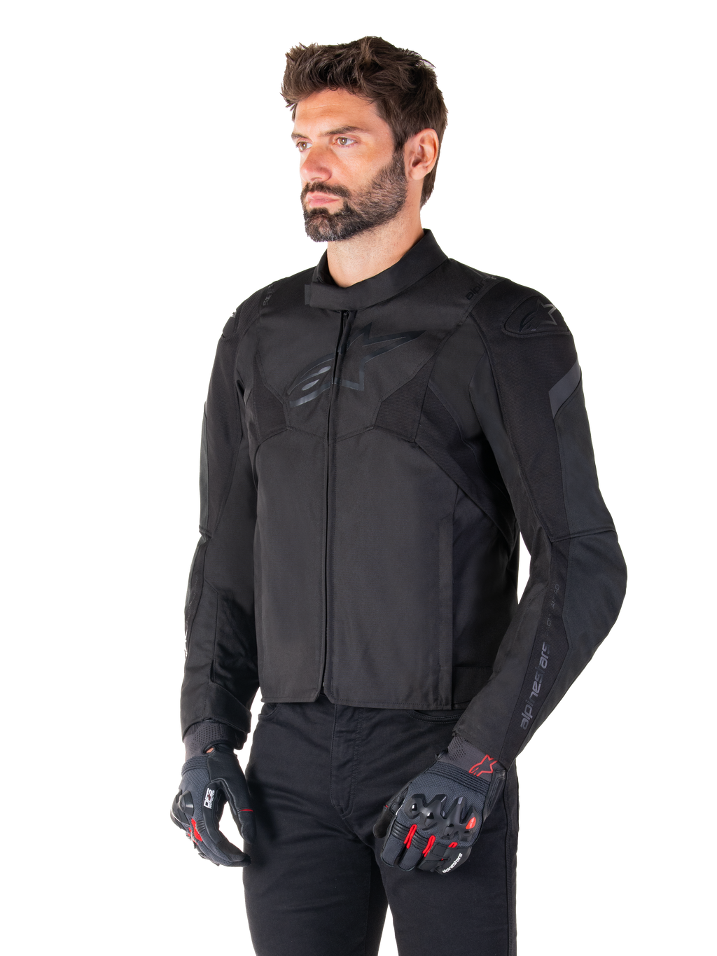 Alpinestars T-Jaws V4 Waterproof Jacket in Black Black, mannelijke rijder met zwarte broek en beschermende handschoenen, strakke sportieve pasvorm, tonale Alpinestars-logo's op de borst en schouders, hoogwaardige textielconstructie