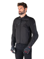 Alpinestars T-Jaws V4 Waterproof Jacket in Black Black, mannelijke rijder met zwarte broek en beschermende handschoenen, strakke sportieve pasvorm, tonale Alpinestars-logo's op de borst en schouders, hoogwaardige textielconstructie