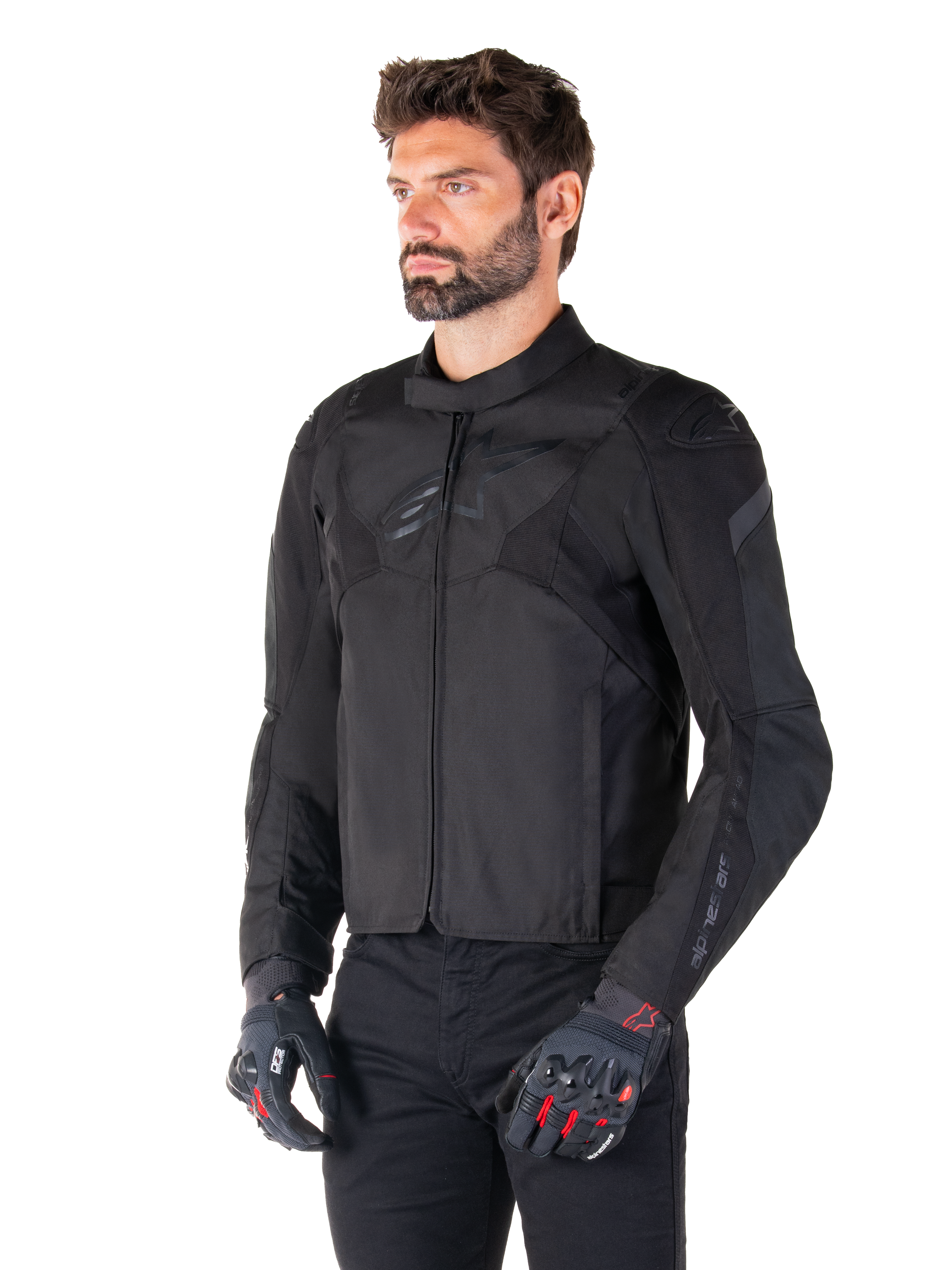 Alpinestars T-Jaws V4 Waterproof Jacket in Black Black, mannelijke rijder met zwarte broek en beschermende handschoenen, strakke sportieve pasvorm, tonale Alpinestars-logo's op de borst en schouders, hoogwaardige textielconstructie