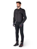 Mannelijk model draagt de Alpinestars T-Jaws V4 Waterdichte Jas in het zwart, gecombineerd met een zwarte motorbroek, zwarte handschoenen met rode accenten en zwarte motorschoenen, met een slanke sportieve pasvorm en subtiele branding, geïsoleerd op een witte achtergrond.