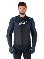 Alpinestars T-Jaws V4 Waterproof Jacket, motorjas, zwart en donkerblauw met Blithe Blue accenten, wit logo op de borst, blauwe tekst op de schouders, gedragen met bijpassende handschoenen, waterdichte textiele motorkleding