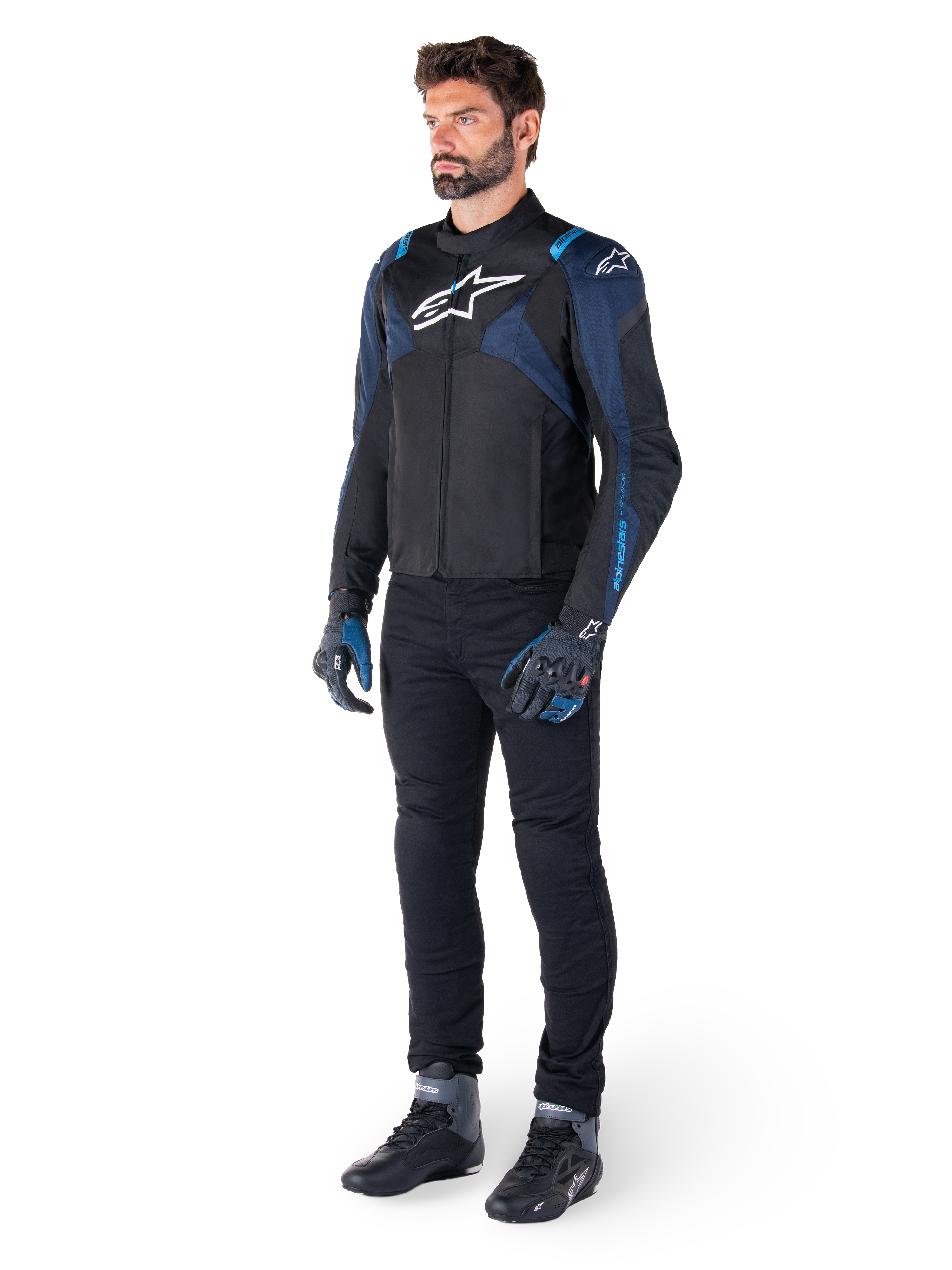 Alpinestars T-Jaws V4 Waterproof Jacket in zwart, donkerblauw en Blithe Blue, gedragen door een model met een zwarte motorbroek en motorlaarzen, voorzien van een wit Alpinestars-logo op de borst en blauwe schouderaccenten, sportieve motoruitrusting