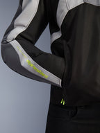 Alpinestars T-Jaws V4 Waterproof Jacket, motorjas, Black Ice Gray Dark Gray, close-up detail van de mouw met fluorescerend gele Alpinestars-branding, textielmateriaal met een zijzak en een multi-paneel ontwerp.
