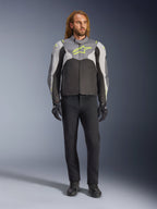 Alpinestars T-Jaws V4 Waterdichte Jas in Black Ice Gray Dark Gray met neongele accenten, gedragen door een mannelijk model, met een sportief silhouet, technische textielconstructie en een opvallend logo op de borst, gecombineerd met een zwarte motorbroek en handschoenen