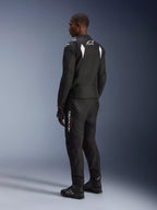 Alpinestars T-SP 1 V2 Waterproof Jacket, zwart en wit, achter- en zijaanzicht op model, gedragen met bijpassende zwarte motorbroek, handschoenen en laarzen, sportieve textiele motoroutfit voor op de weg